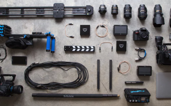 Flat lay of Panasonic and Nikon camera gear, lenses, cables, laptop, and filmmaking accessories arranged neatly on a surface, captured in 4K Ultra HD detail.