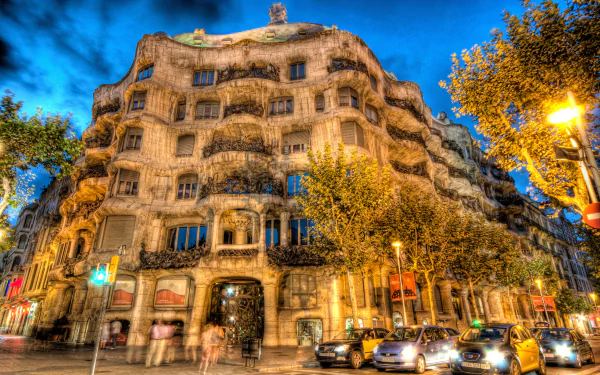 4K Ultra HD HDR cityscape of Barcelona showcasing unique architecture along a bustling street at dusk, vibrant lights illuminating the intricate building facade.