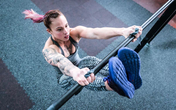 HD PC desktop wallpaper and background: tattooed gymnast performing a high-bar leg raise in a gym, dynamic gymnastics sports action captured in sharp detail.