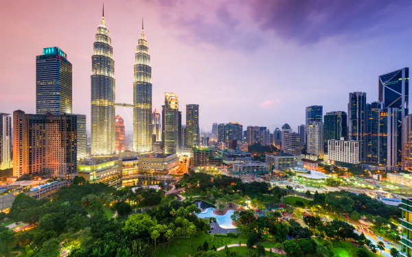 Panoramic 4K Ultra HD view of Kuala Lumpur cityscape at dusk, featuring illuminated buildings including the Petronas Towers, set against a colorful sky in Malaysia.