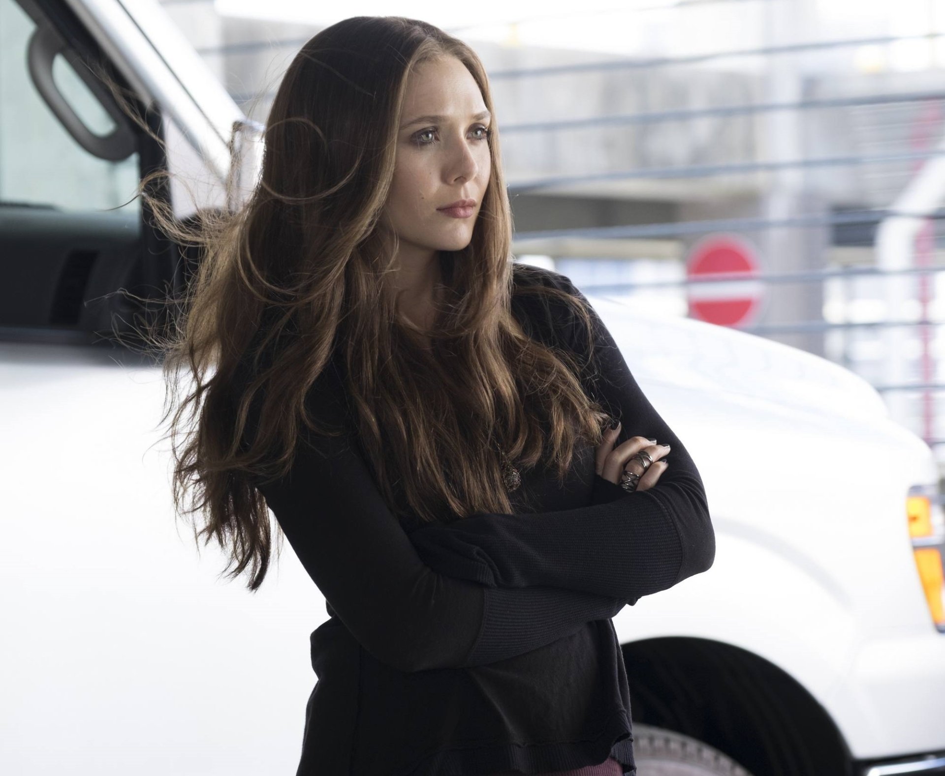 Elizabeth Olsen as Scarlet Witch in Captain America: Civil War stands with arms crossed in this HD desktop wallpaper and background.