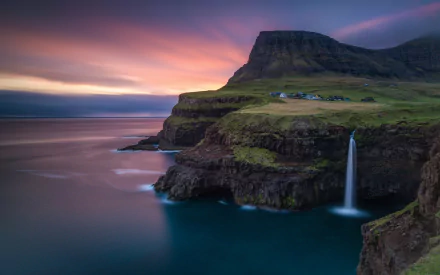 HD desktop wallpaper of Gásadalur featuring a dramatic coastal cliff, waterfall, and vibrant dusk sky, showcasing a stunning man-made perspective of nature.