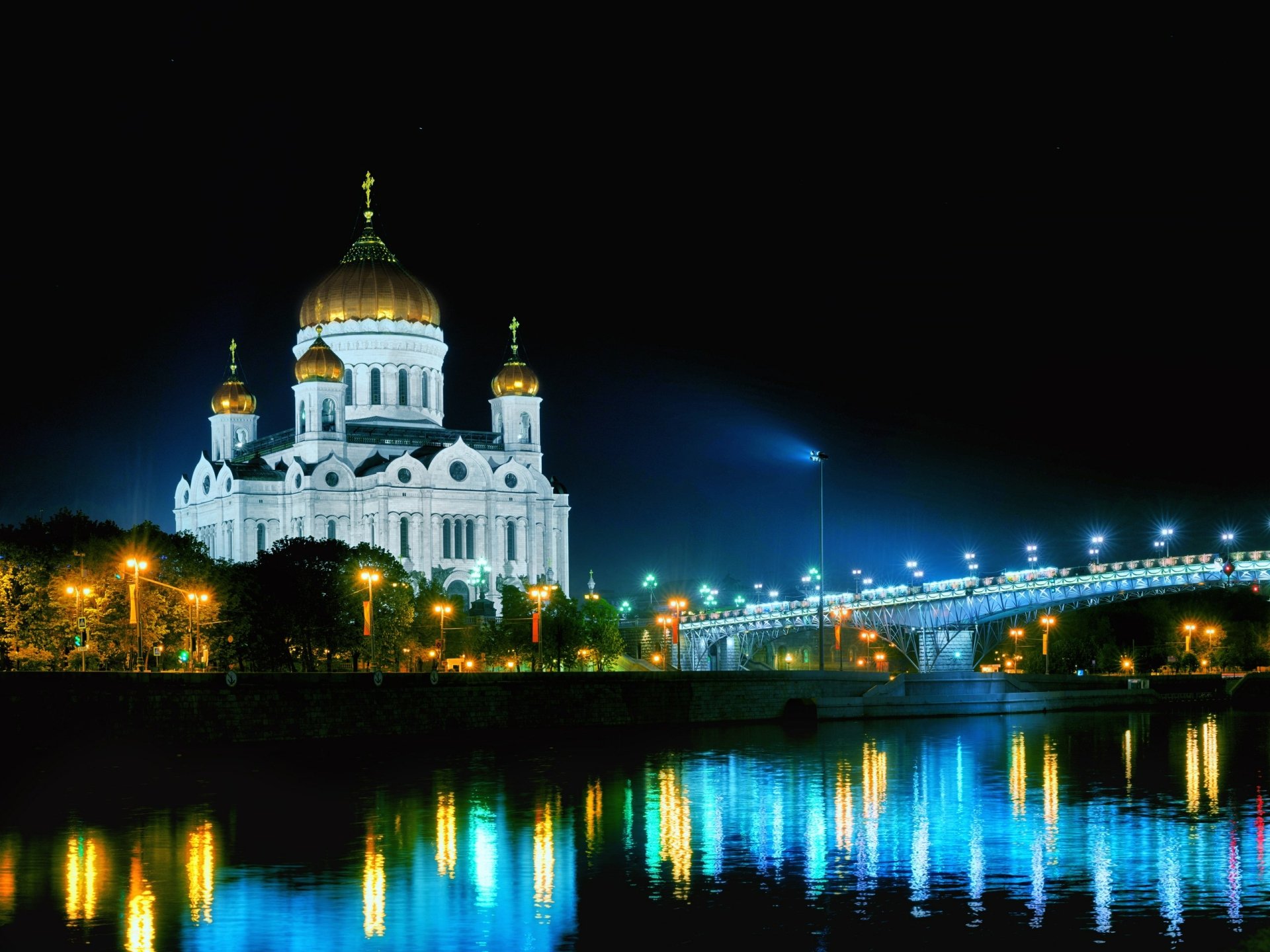 Night view of the illuminated Cathedral of Christ the Saviour beside a lit bridge, reflections shimmering on the river — 2K Quad HD desktop wallpaper/background.
