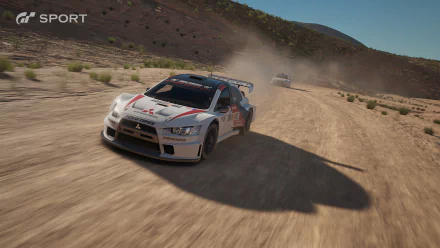 HD PC desktop wallpaper from the video game Gran Turismo Sport: white rally car kicking up dust while drifting on a sunlit mountain dirt road.