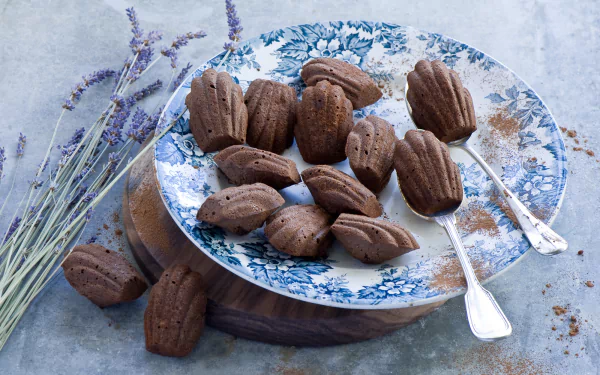 HD PC desktop wallpaper of chocolate Madeleines on a blue floral plate with lavender sprigs and two silver spoons — food-themed background.