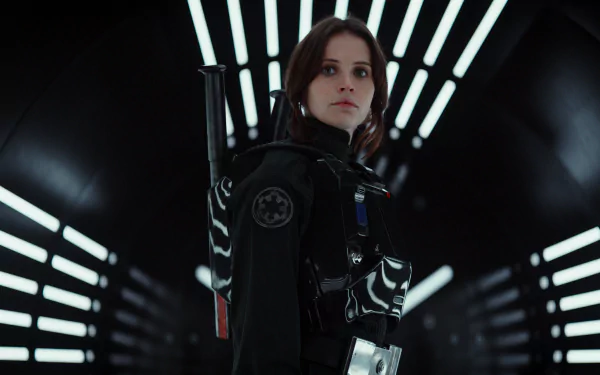 HD desktop wallpaper featuring Jyn Erso, played by Felicity Jones, from the movie Rogue One: A Star Wars Story. Jyn stands in an illuminated corridor, dressed in her Star Wars Rebel gear.