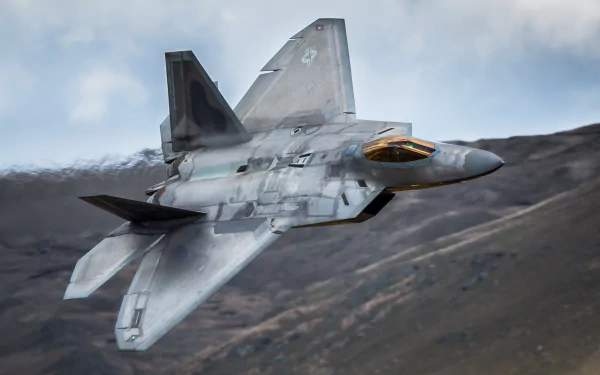 A striking image of a Lockheed Martin F-22 Raptor jet fighter in flight, showcasing its sleek design against a dramatic mountainous backdrop. A high-definition wallpaper for aviation enthusiasts.