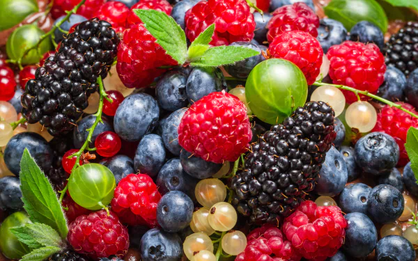 Close-up of fresh blackberries, blueberries, raspberries, and other berries with green leaves in vibrant colors as a 4K Ultra HD PC desktop wallpaper background.