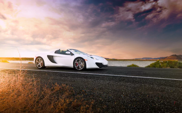 A white McLaren MP4-12C Spider supercar parked on a coastal road under a dramatic sky, captured in high-definition for a PC desktop wallpaper.