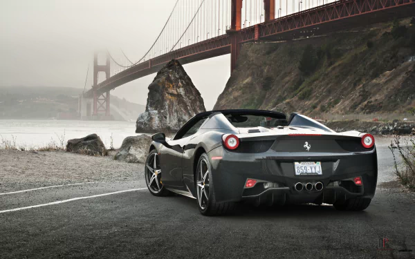 A sleek black Ferrari 458 Spider parked by the coast, with the iconic Golden Gate Bridge in the background. This stunning 4K Ultra HD image captures luxury and scenery.