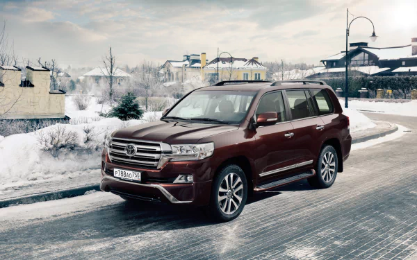 A maroon Toyota Land Cruiser SUV parked on a snowy road in a winter village setting, captured in 4K Ultra HD for PC desktop wallpaper and background.