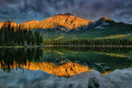 HD PC desktop wallpaper: golden mountain and forest reflected in a glassy lake beneath dramatic clouds — a nature landscape with mirror-like reflection.