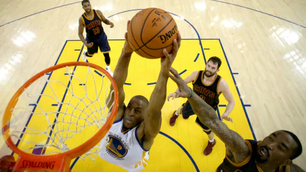 A Golden State Warriors player goes for a powerful dunk against Cleveland Cavaliers defenders in an intense basketball game. HD desktop wallpaper and background.