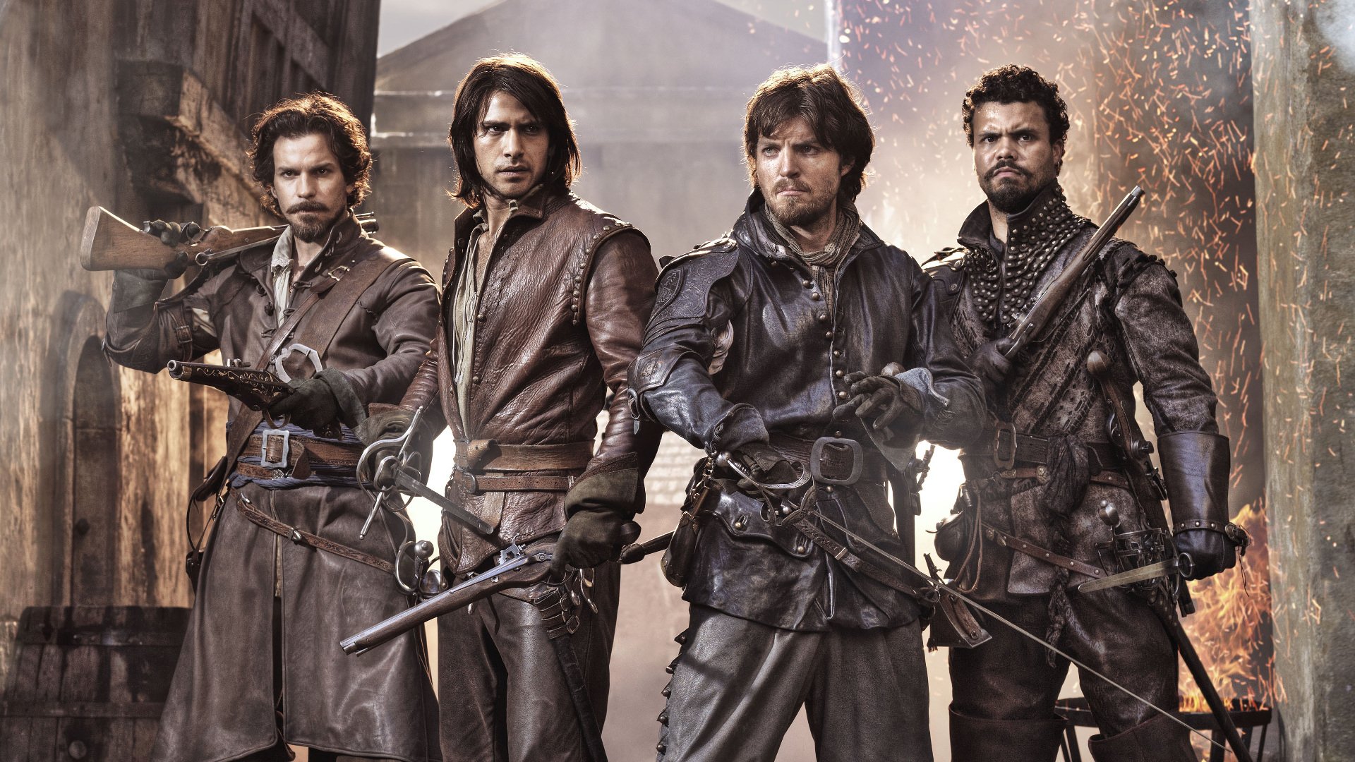 HD PC desktop wallpaper: four musketeers from the TV show The Musketeers in leather, swords drawn, standing in a gritty, sunlit alley.