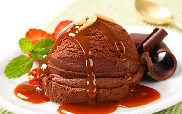 Rich chocolate ice cream drizzled with caramel sauce, garnished with fresh mint, strawberries, and chocolate curls for a vibrant summer dessert in 4K Ultra HD.