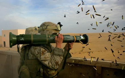 A soldier fires an AT4 military rocket, with spent casings flying through the air, set against a desert backdrop, creating a striking HD desktop wallpaper.