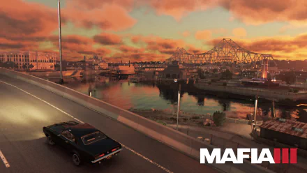 A scenic view from Mafia III, featuring a classic car on a highway with a vibrant sunset and a city skyline reflecting on the water. An immersive HD wallpaper for fans of the game.