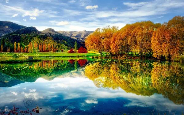 A serene lake landscape in fall, surrounded by vibrant autumn trees reflecting on the calm water under a clear blue sky, showcasing the beauty of nature in high definition.