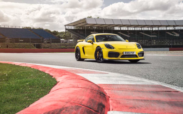 Yellow Porsche Cayman GT4 on a racetrack corner by the grandstand — high-detail 4K Ultra HD PC desktop wallpaper/background.