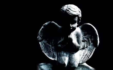 HD desktop wallpaper featuring a man-made cherub statue with detailed wings illuminated against a dark background.