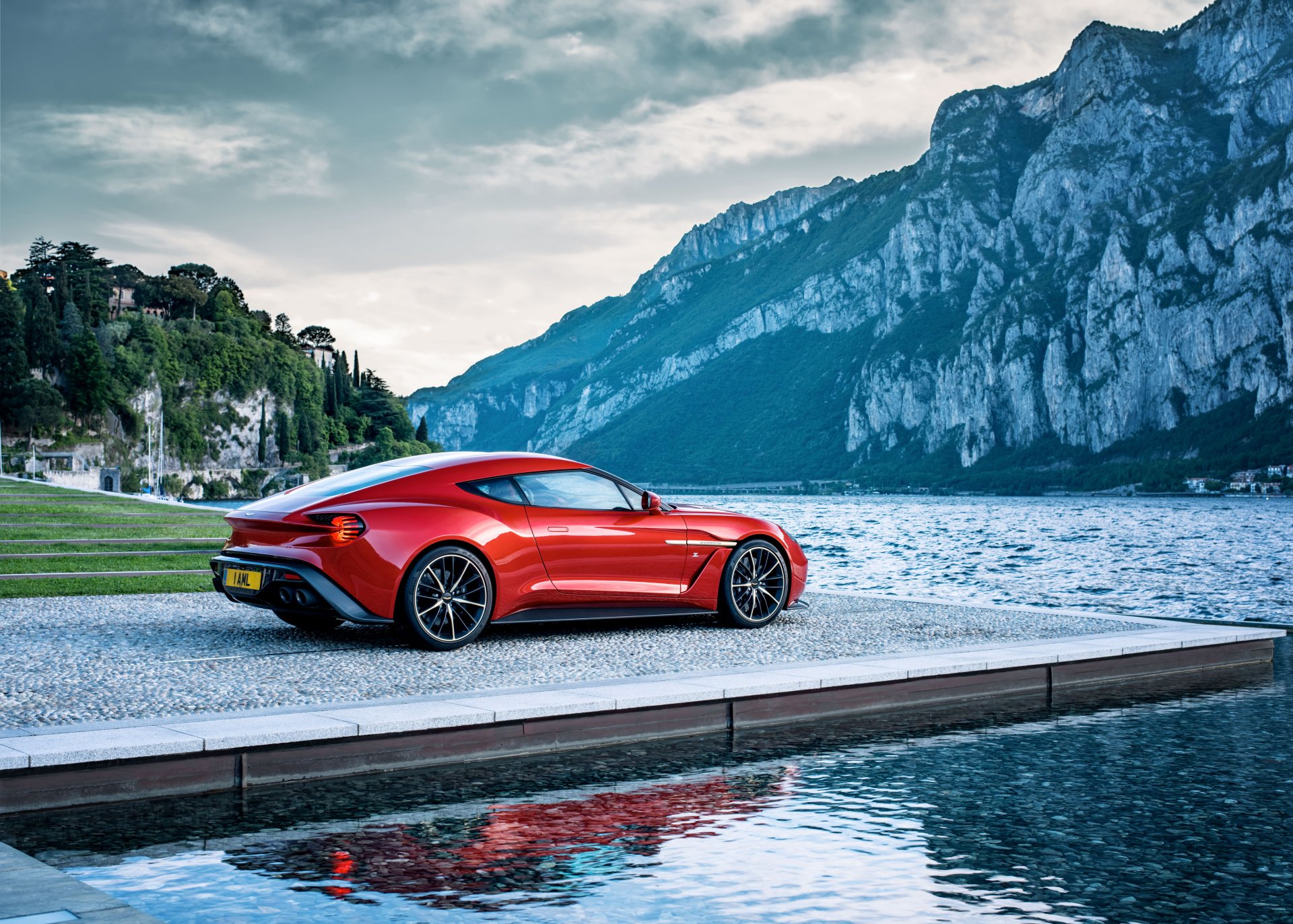 Red Aston Martin Vanquish grand tourer by a mountain lake, reflected in the water — 4K Ultra HD PC desktop wallpaper/background.