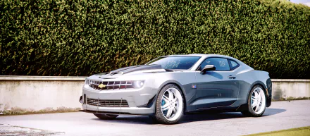 HD PC desktop wallpaper featuring a sleek Chevrolet Camaro from Grand Theft Auto V parked in front of a tall green hedge.