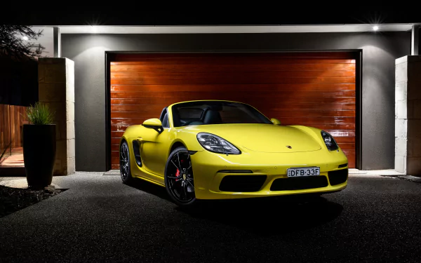 Yellow Porsche Boxster sports car parked in front of a modern garage, showcased in sharp 4K Ultra HD detail for PC desktop wallpaper and background.
