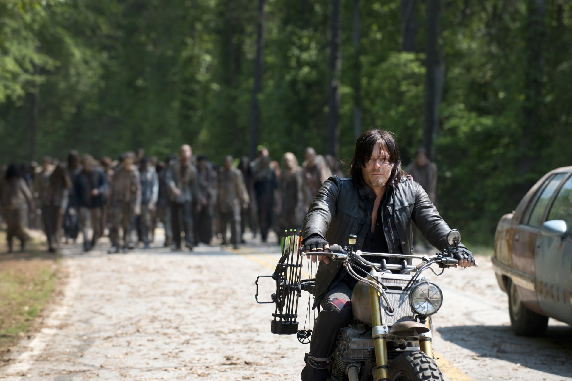 Daryl Dixon, portrayed by Norman Reedus, rides his motorcycle through a zombie-infested landscape from the TV show The Walking Dead in this HD wallpaper.