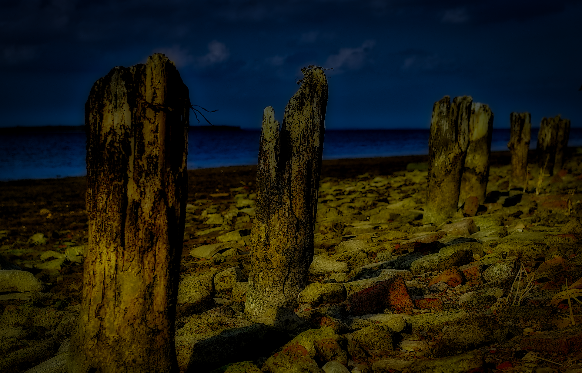 HD PC desktop wallpaper and background: nature beach scene with weathered wooden posts on a rocky shore, ocean water and dark blue horizon under a night sky.