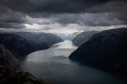 A stunning view of Lysefjord in Norway, where majestic mountains meet a tranquil waterway under a dramatic sky filled with clouds, captured as an 8K Ultra HD background.
