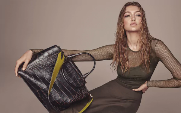 Blonde American model Gigi Hadid poses confidently with a stylish black bag, showcasing a chic look in this high-definition desktop wallpaper.