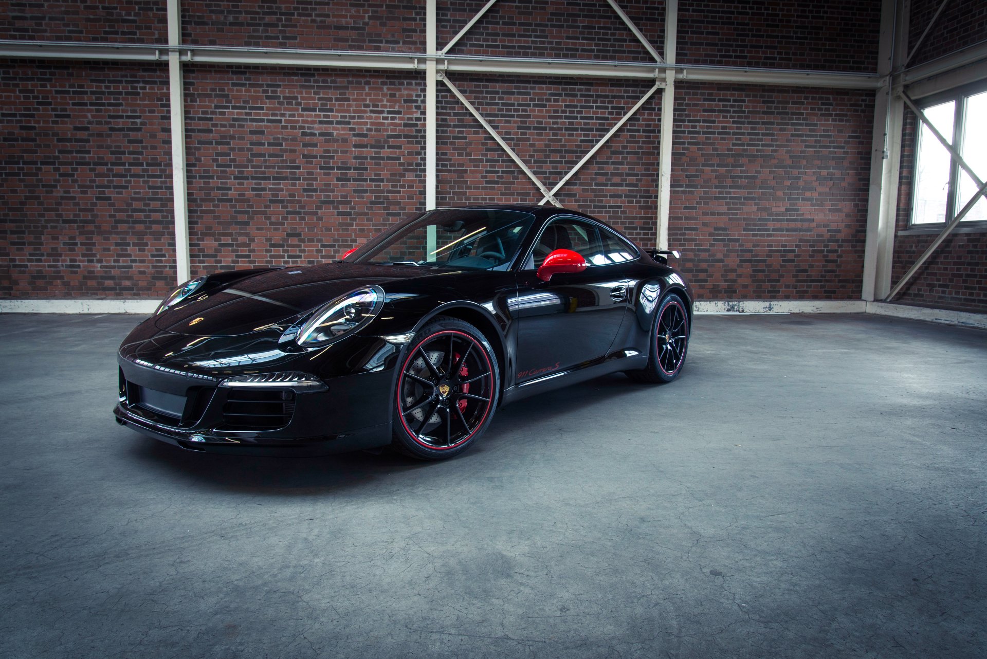 Black Porsche 911 Carrera parked in an industrial-style garage, showcased in a 4K Ultra HD PC desktop wallpaper and background.