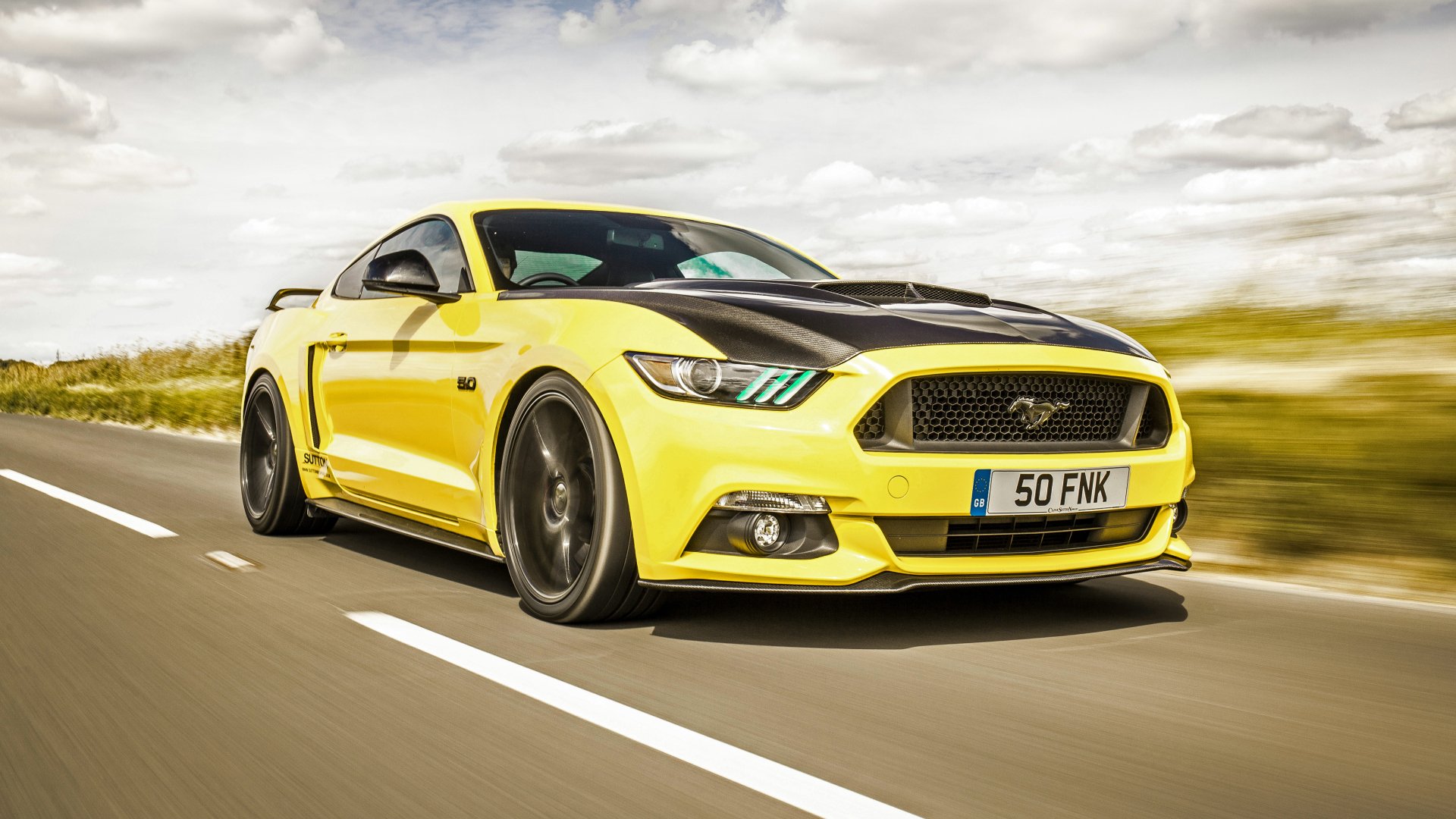 Yellow Ford Mustang GT muscle car driving on a road, captured in 4K Ultra HD as a vibrant PC desktop wallpaper and background.