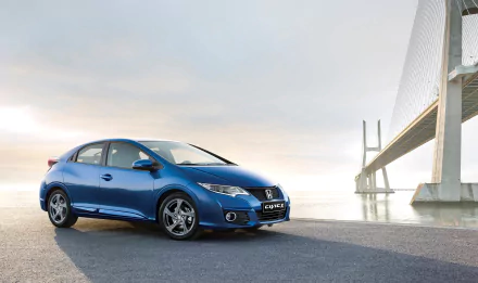 A sleek blue Honda Civic parked beside a modern bridge, set against a serene sky. This HD image captures the compact car's stylish design and urban landscape backdrop.
