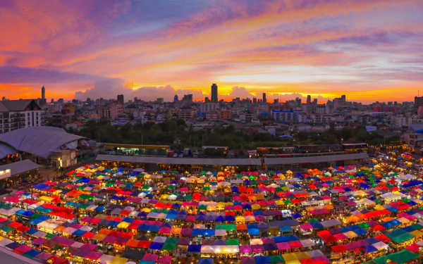 Vibrant sunset over Bangkok’s colorful market with cityscape and buildings, showcasing a lively and dynamic urban scene in Thailand.