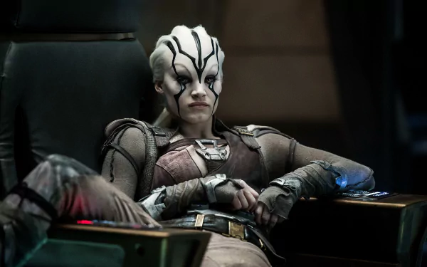 Sofia Boutella as Jaylah from Star Trek Beyond relaxes confidently in a futuristic chair, showcasing her striking character design in this 4K Ultra HD wallpaper.