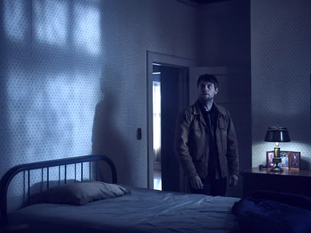 2K Quad HD PC wallpaper: moody, dim bedroom with a man in a jacket standing by an open door, atmospheric scene from the TV show Outcast.