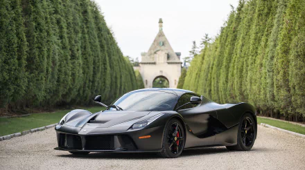 A sleek black Ferrari LaFerrari parked along a luxurious path, framed by meticulously trimmed hedges and a distinctive architectural backdrop, showcasing its stunning design and elegance.