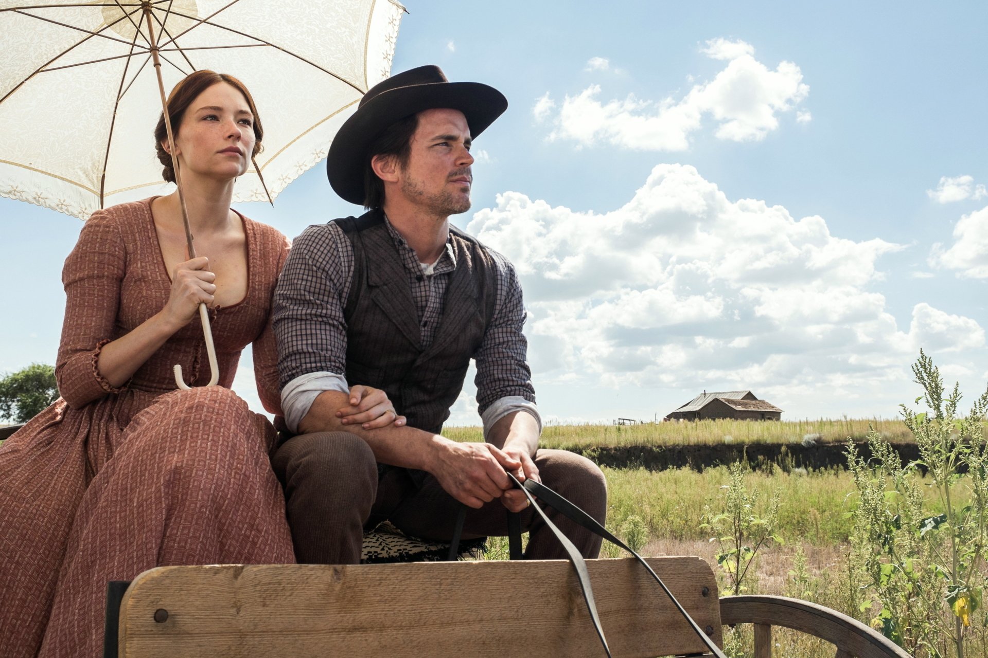 HD desktop wallpaper featuring Haley Bennett and a co-star from The Magnificent Seven (2016) movie, seated outdoors under a bright sky.