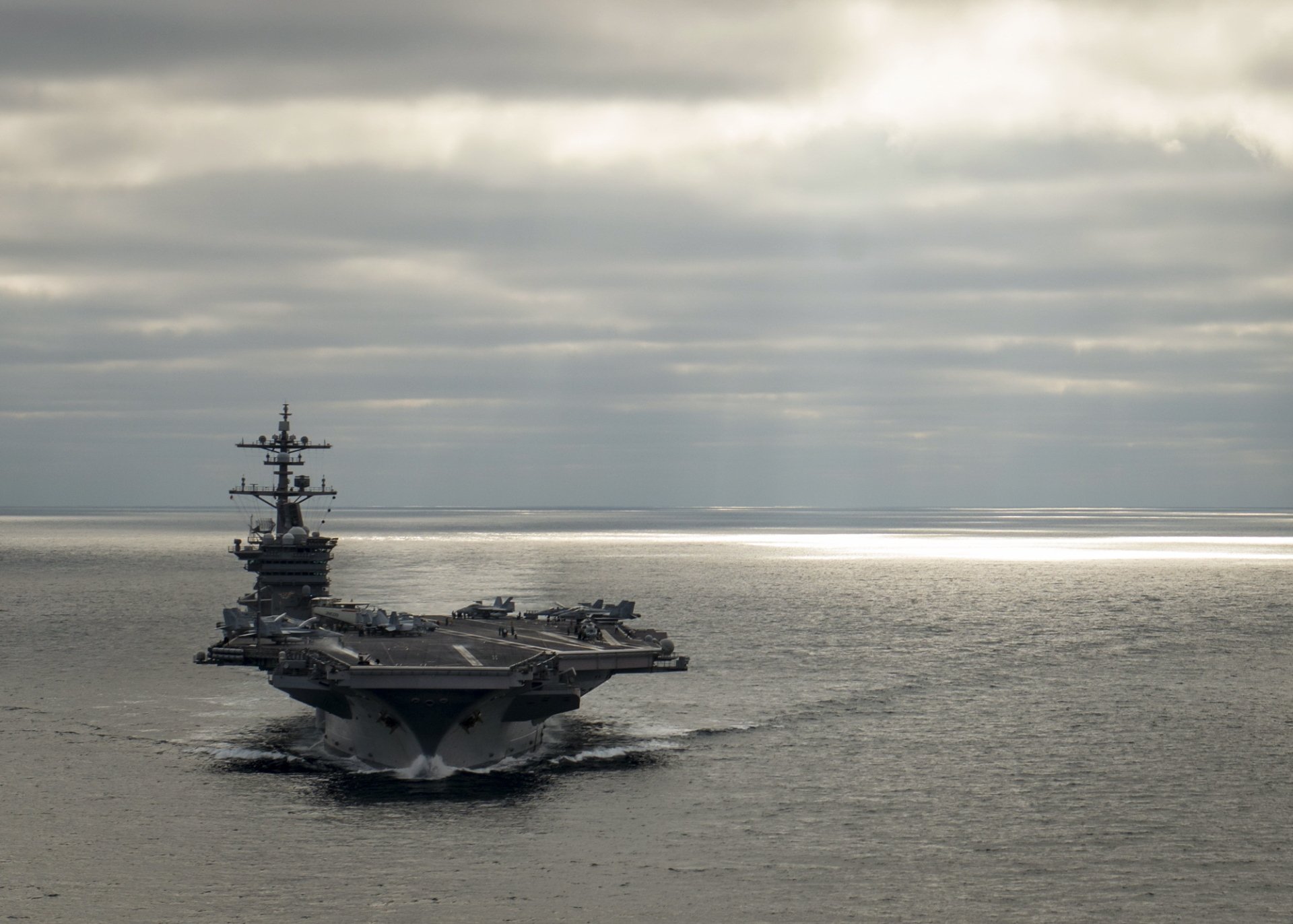 An impressive view of the USS Carl Vinson (CVN-70), a military aircraft carrier, navigating through calm waters under a cloudy sky, showcased as a high-definition desktop wallpaper.
