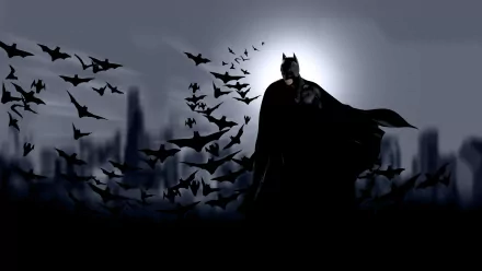 HD desktop wallpaper featuring Batman from the movie Batman Begins standing against a dark city skyline, surrounded by a swarm of bats, under a glowing moon.