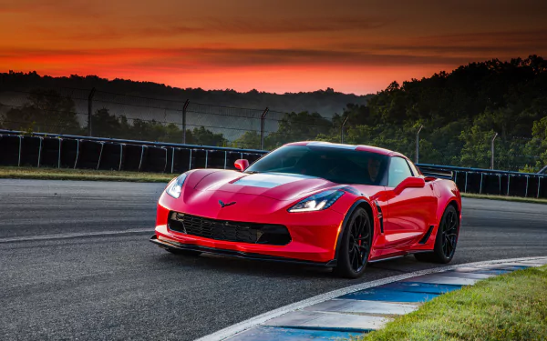 A red Chevrolet Corvette (C7) sports car on a racetrack during sunset, captured in high-definition for a PC desktop wallpaper and background.