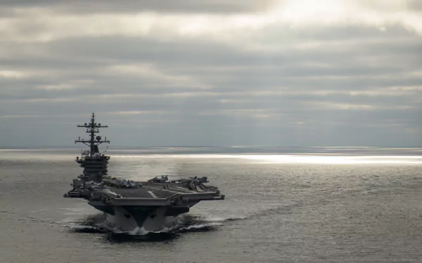 An impressive view of the USS Carl Vinson (CVN-70), a military aircraft carrier, navigating through calm waters under a cloudy sky, showcased as a high-definition desktop wallpaper.