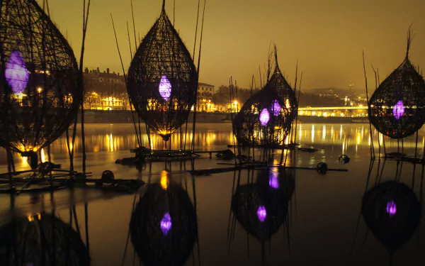 A serene night scene of the River Lyon in France, featuring illuminated reflections from artistic structures on the water, creating a stunning photographic backdrop.