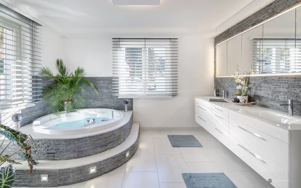 HD PC desktop wallpaper of a modern, man-made bathroom featuring a corner whirlpool tub, large mirror, sleek white cabinetry, and natural light from window blinds.