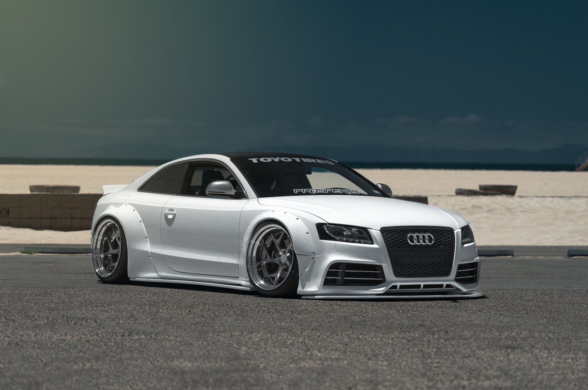 A sleek white Audi S5 grand tourer with tuning modifications, set against a minimalist urban backdrop, captured as an HD PC desktop wallpaper.
