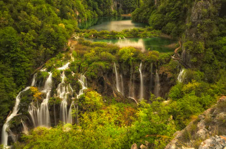 A breathtaking view of Plitvice Lake National Park, featuring lush greenery, cascading waterfalls, and tranquil waters, perfect for nature enthusiasts and desktop wallpaper.