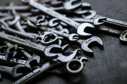 HD desktop wallpaper featuring a close-up of various man-made spanners and wrenches scattered on a dark surface.