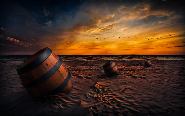 4K Ultra HD artistic beach wallpaper showing barrels on sand under a dramatic sunset sky with birds flying near the horizon.