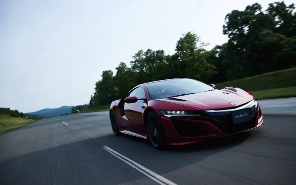 A sleek red Honda NSX supercar speeds down a tree-lined road, captured in stunning 4K Ultra HD for a dynamic PC desktop wallpaper.
